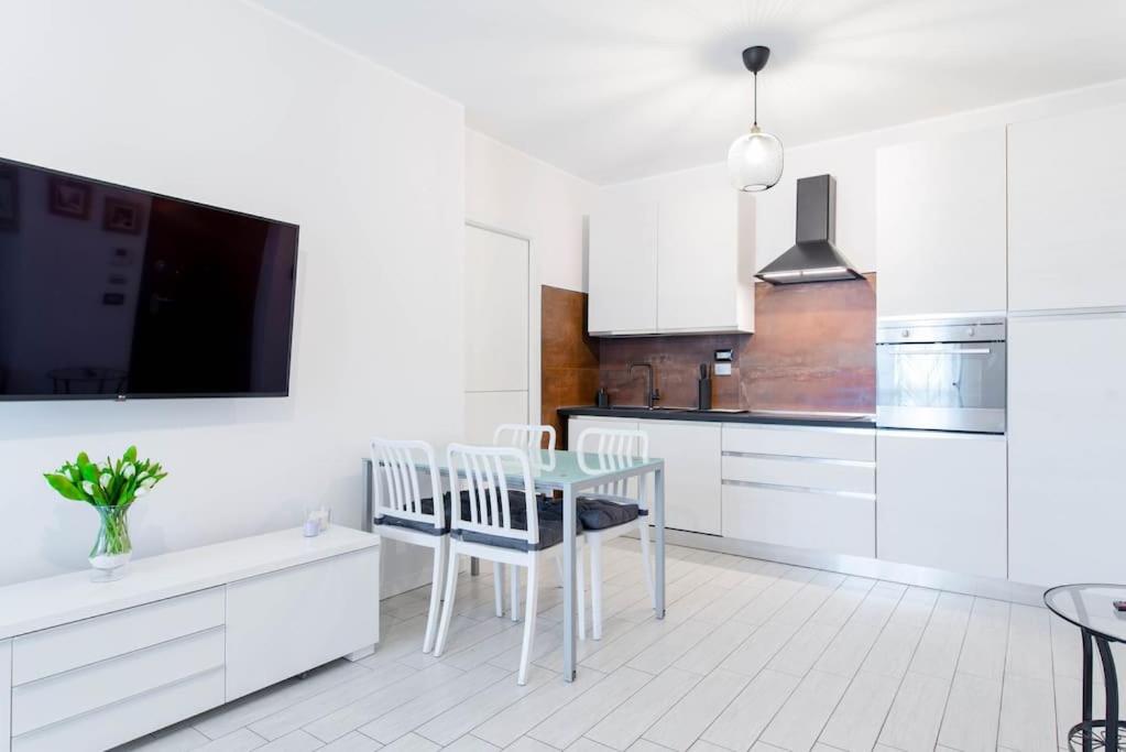a kitchen with white cabinets and a table and chairs at Appartamento comodo a Mirafiori - Santorelli Home in San Paolo