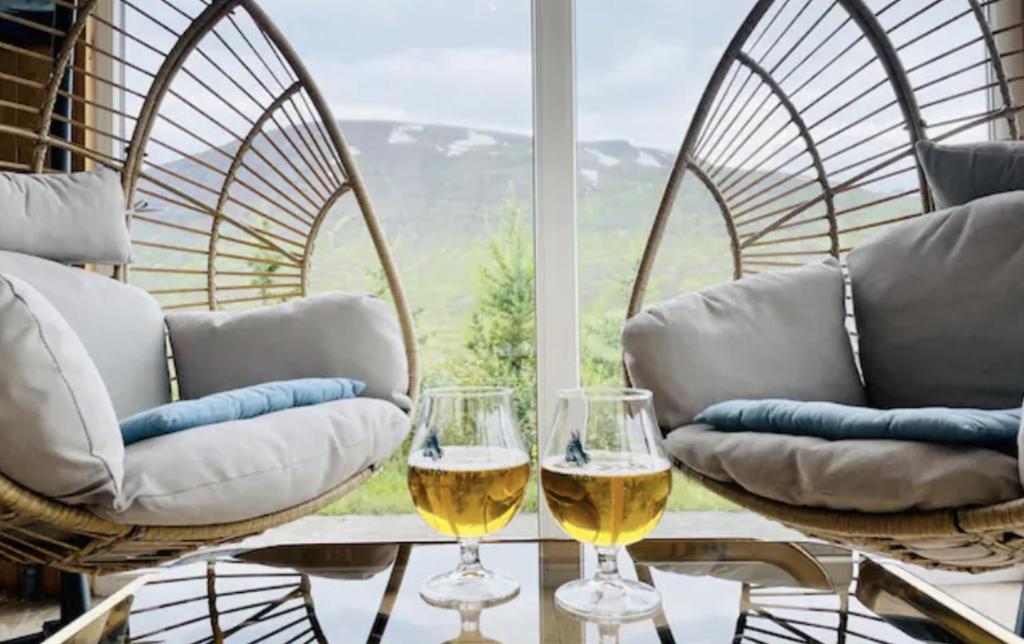 dois copos de vinho branco sentados numa mesa em frente a uma janela em Hidden Cottages 