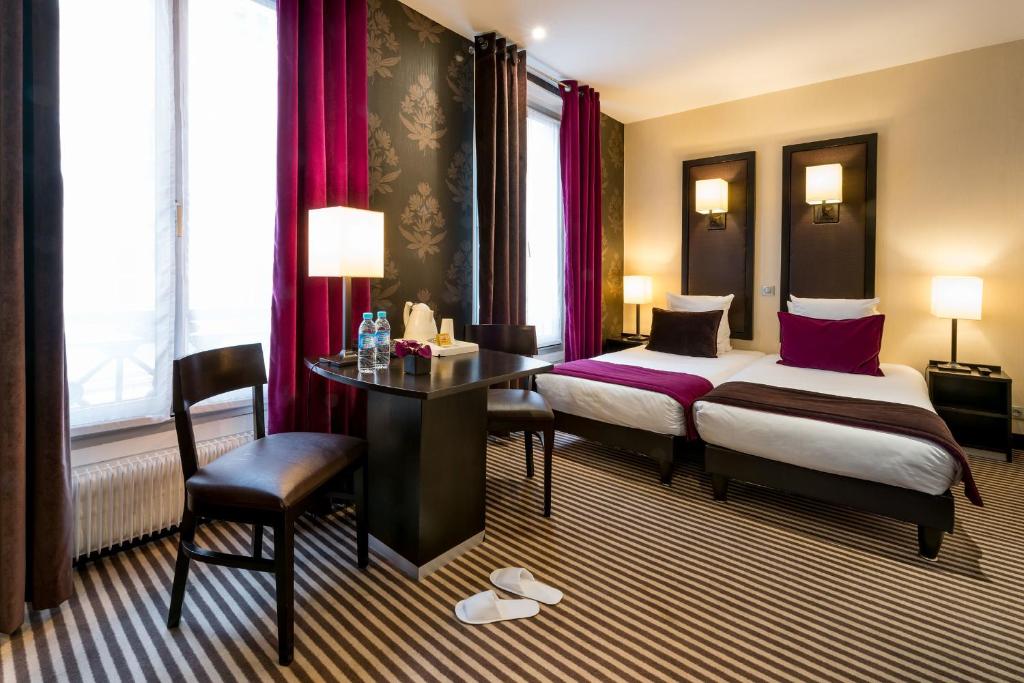 a hotel room with two beds and a table and a desk at Hotel Pax Opera in Paris