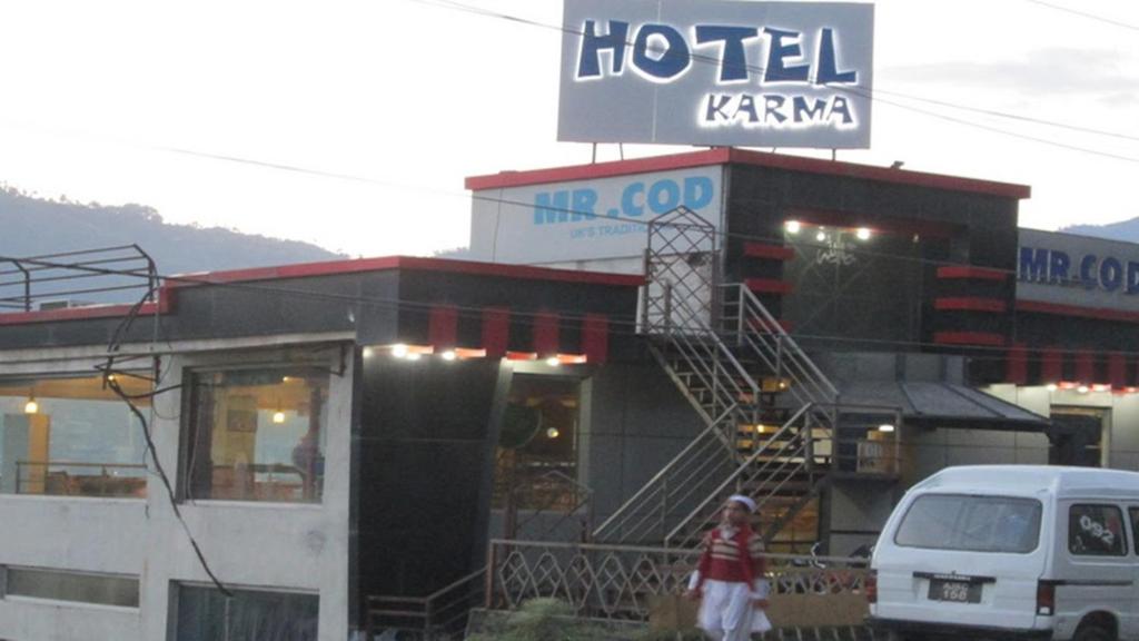 un hotel karma con una mujer parada frente a él en Hotel Karma Muzaffarabad, en Muzaffarabad