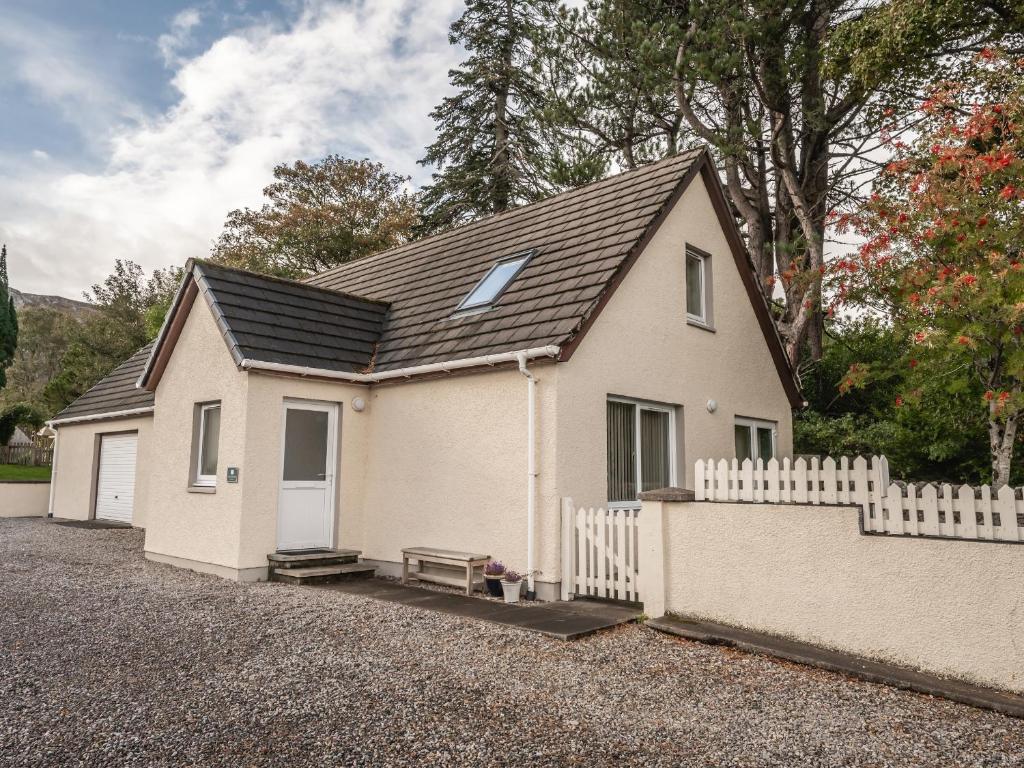 a small white house with a white fence at The Cottage at Corriness House in Achnasheen