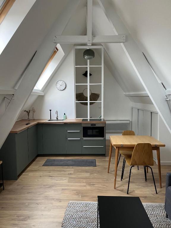 une cuisine mansardée et une salle à manger avec une table. dans l'établissement Le426, Charmant F2 refait à neuf, à Mouvaux