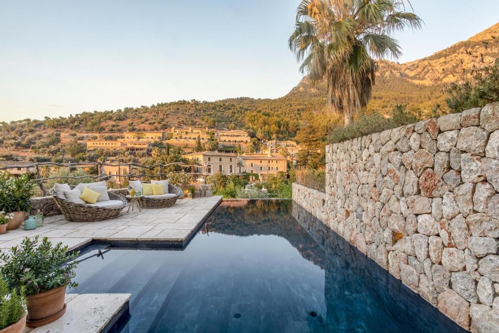 a pool with a stone wall and a villa at Casa Berne - Deia in Deia