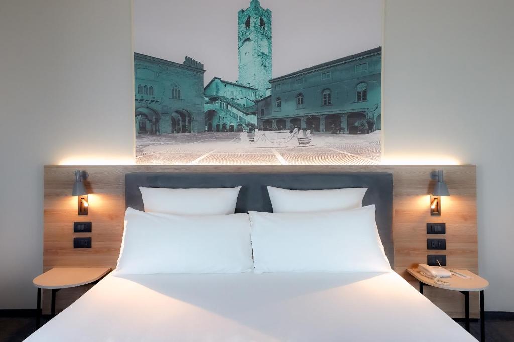 um quarto com uma cama branca e uma torre do relógio em Mercure Bergamo Centro Palazzo Dolci em Bérgamo