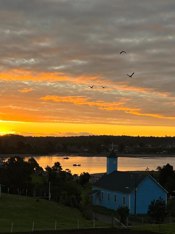 um grupo de aves que sobrevoam um lago ao pôr-do-sol em Cabañas Sol Del Mar em Ancud