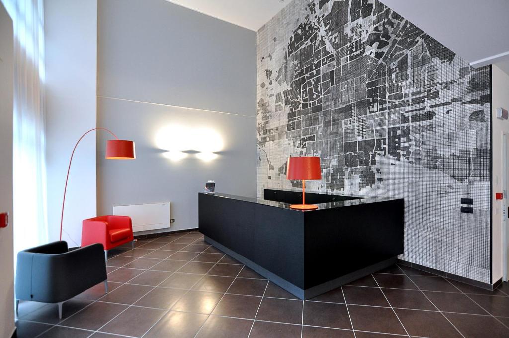 eine Lobby mit einem Schreibtisch und einem roten Stuhl in der Unterkunft BB Hotels Aparthotel Arcimboldi in Mailand