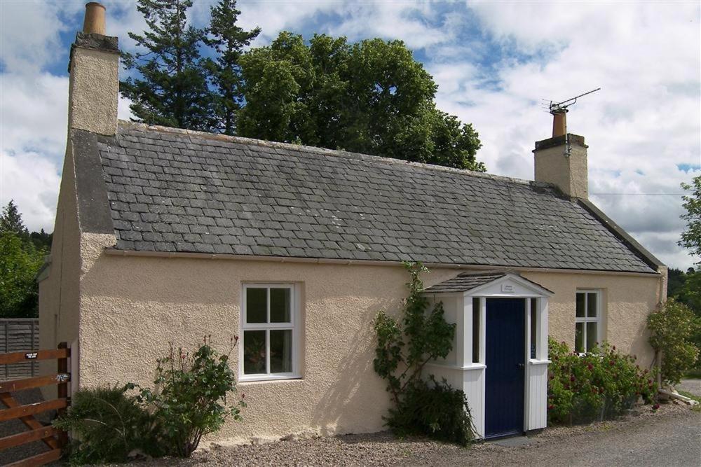 a small white house with a blue door at Manse Cottage in Elgin