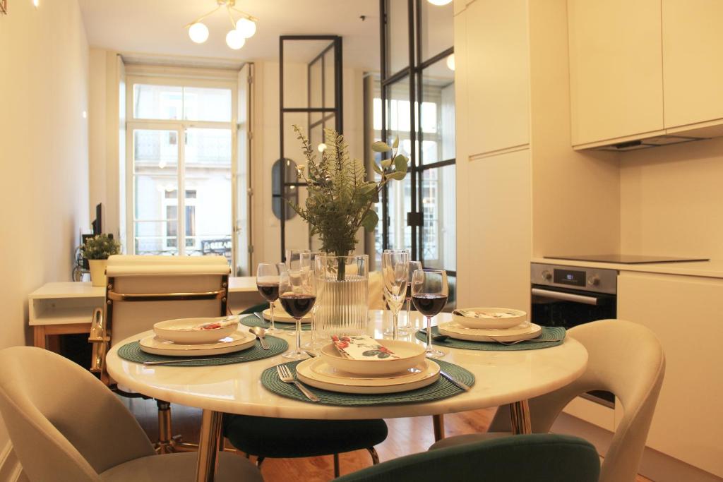 uma mesa de jantar com pratos e copos de vinho em Aliados Sunny Flat no Porto