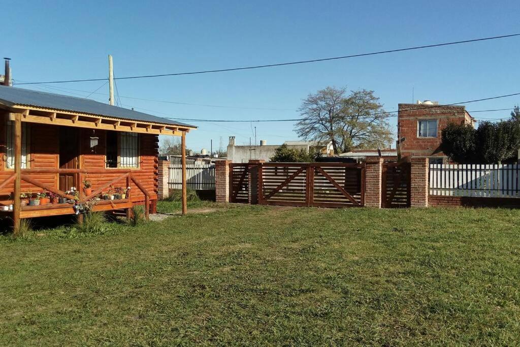 una casa de madera con una valla junto a un patio en Cabaña meolos en Tandil