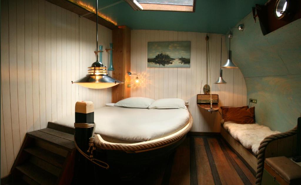 a bedroom with a large white bed and a couch at Boat 'Opoe Sientje' in Nijmegen