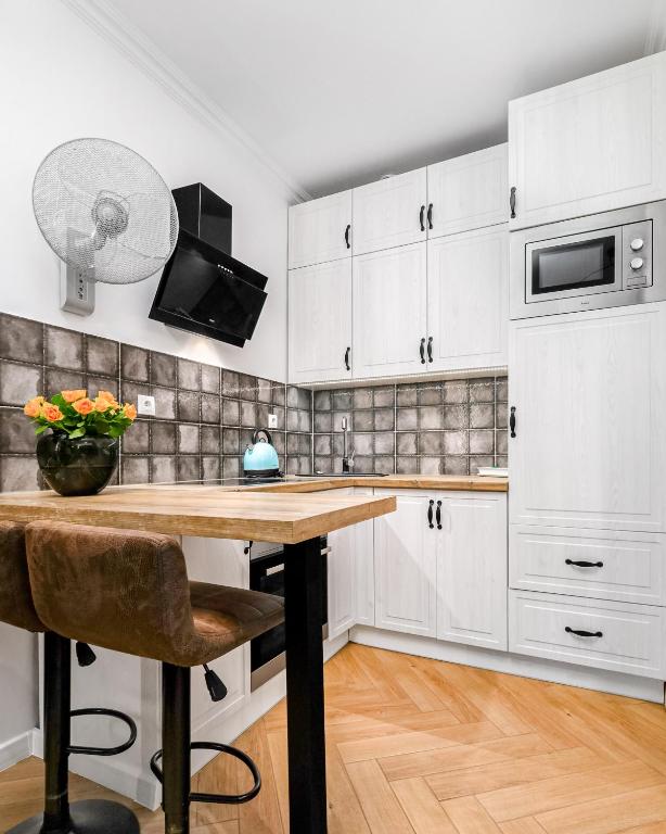 kuchnia z białymi szafkami i drewnianym stołem w obiekcie Jacuzzi & Bike Apartment, Krakow w Krakowie