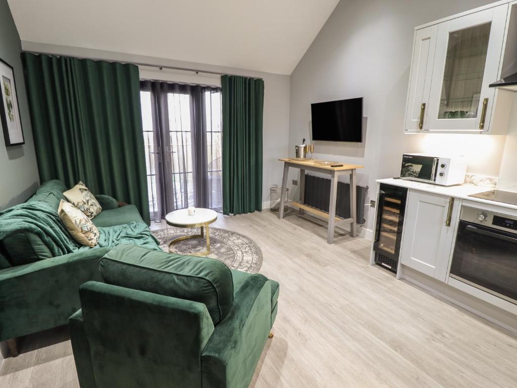 ein Wohnzimmer mit einem grünen Sofa und einer Küche in der Unterkunft Willow in Hull