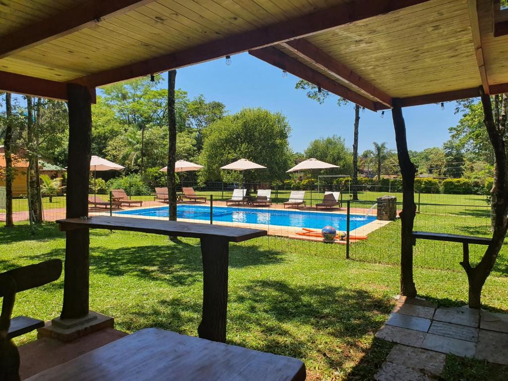 a pool with a picnic table and umbrellas at Cabañas Selva Verde in Puerto Iguazú