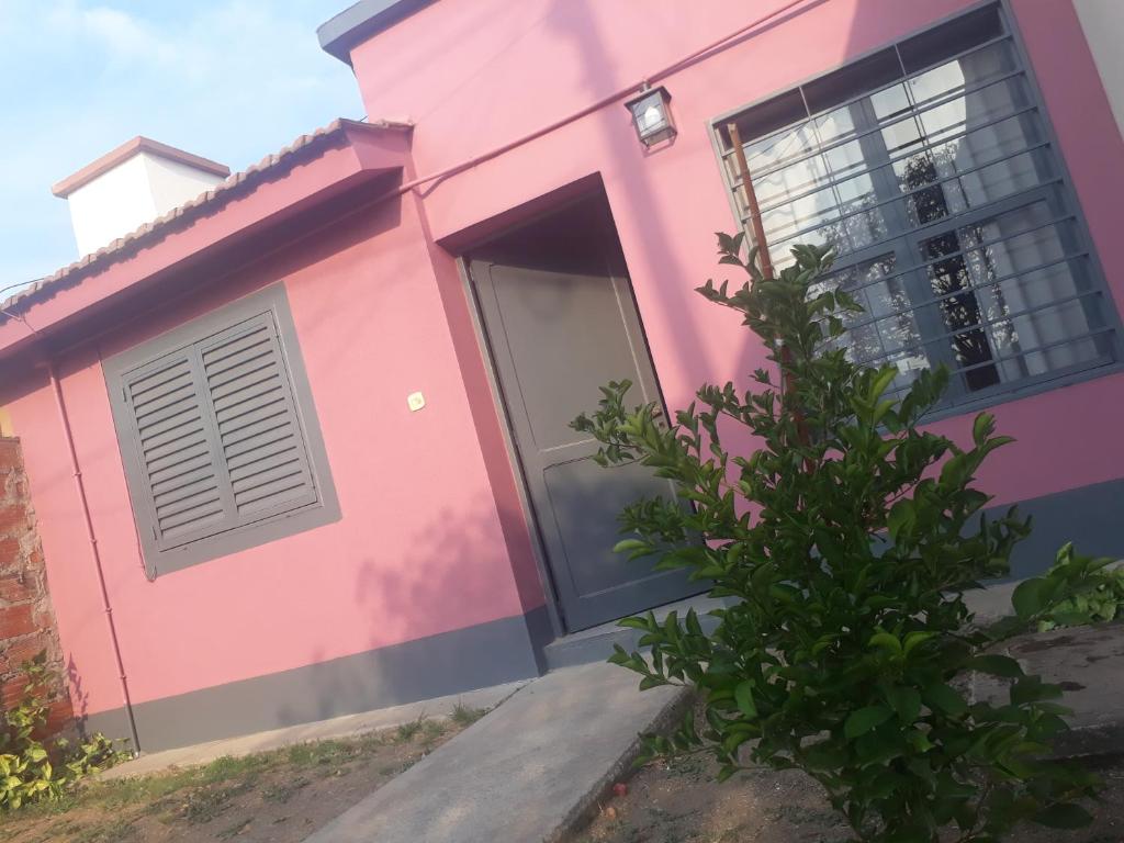 una casa rosa con una puerta y un árbol en AZUL Y LUNA en Vaqueros