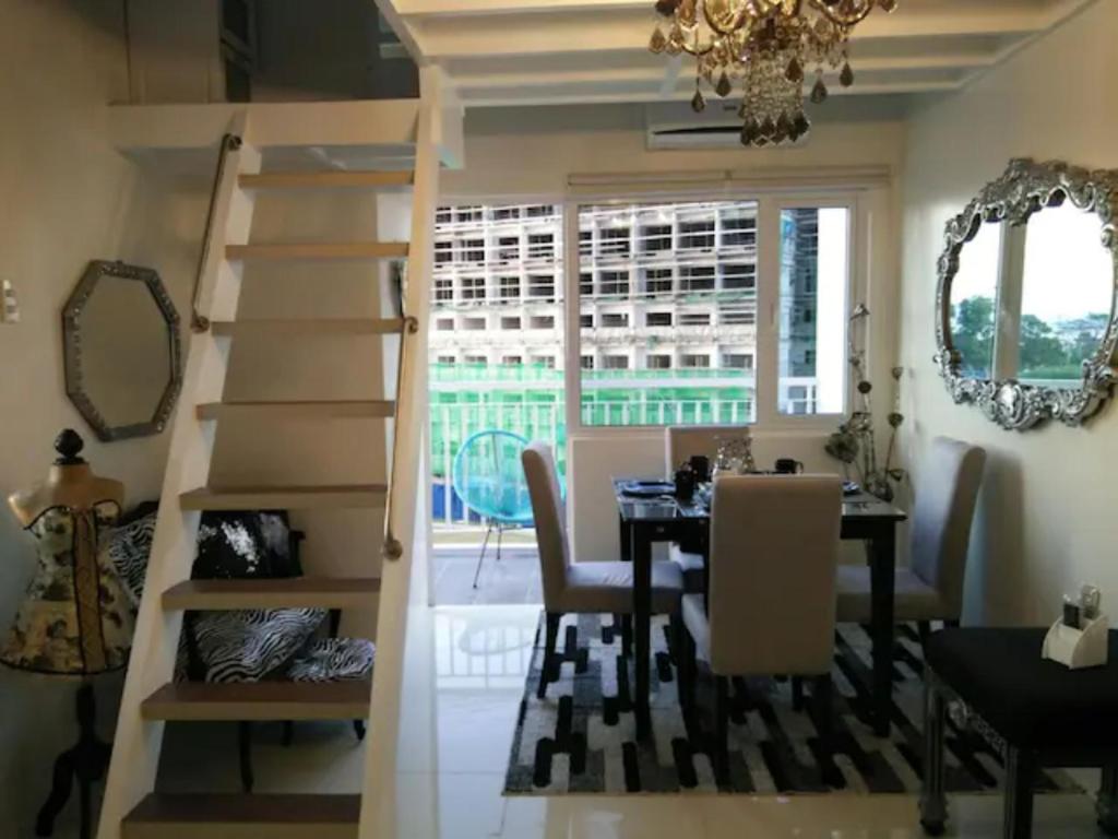 a dining room with a staircase and a table and a chandelier at SMDC Wind Loft Bedroom 101 Facing Amenities with WIFI and Parking in Tagaytay