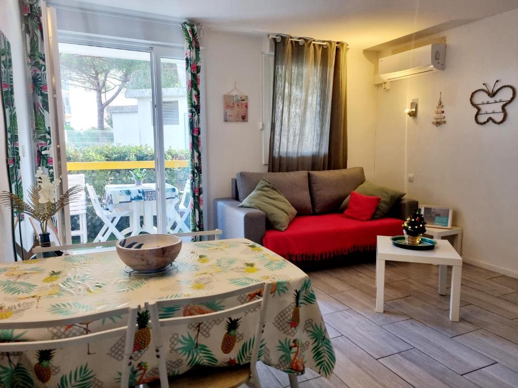 a living room with a red couch and a table at Plein cœur du Grau du Roi - Les Cigales de la Mer - 100m de la plage in Le Grau-du-Roi