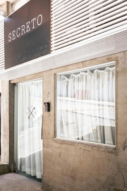 a store front with a window with white curtains at Secreto Quartos in Rio de Janeiro