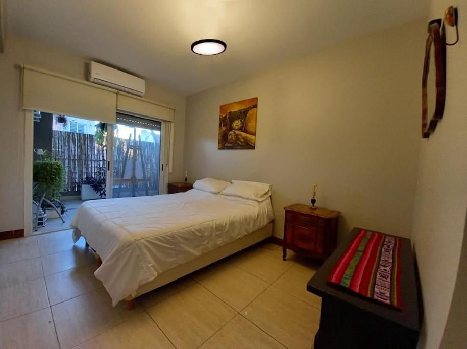 1 dormitorio con cama, mesa y ventana en Moderno piso de diseño c/ cochera cubierta en Saavedra en Buenos Aires