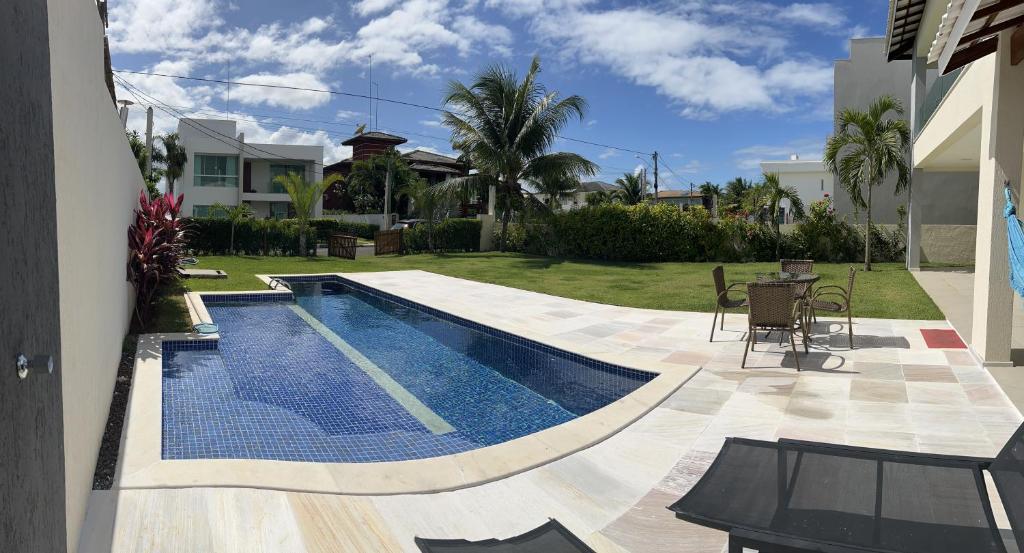 a swimming pool in a yard with a table and chairs at Venha se hospedar no Paraíso de Guarajuba in Camaçari