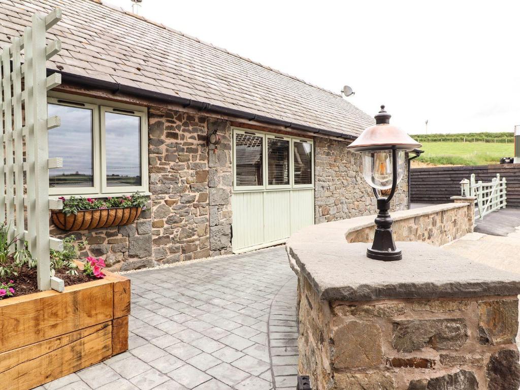 a stone house with a lamp on a patio at Beudy Bach in Aberhafesp