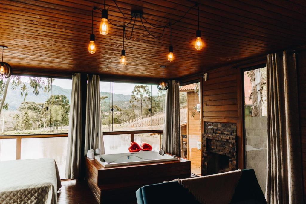 a bedroom with a tub in front of a window at Recanto- Pousada Cachoeira da Neve in Urubici