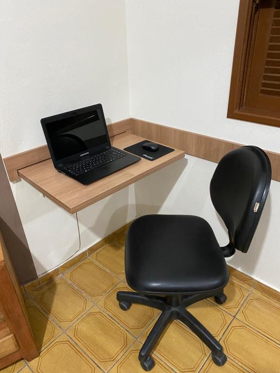 a laptop computer sitting on a desk with a chair at Casa aconchegante à 400m da Praia da Tartaruga - Ar condicionado - WIFI 450MB - Netflix - Cozinha Completa - Garagem in Rio das Ostras