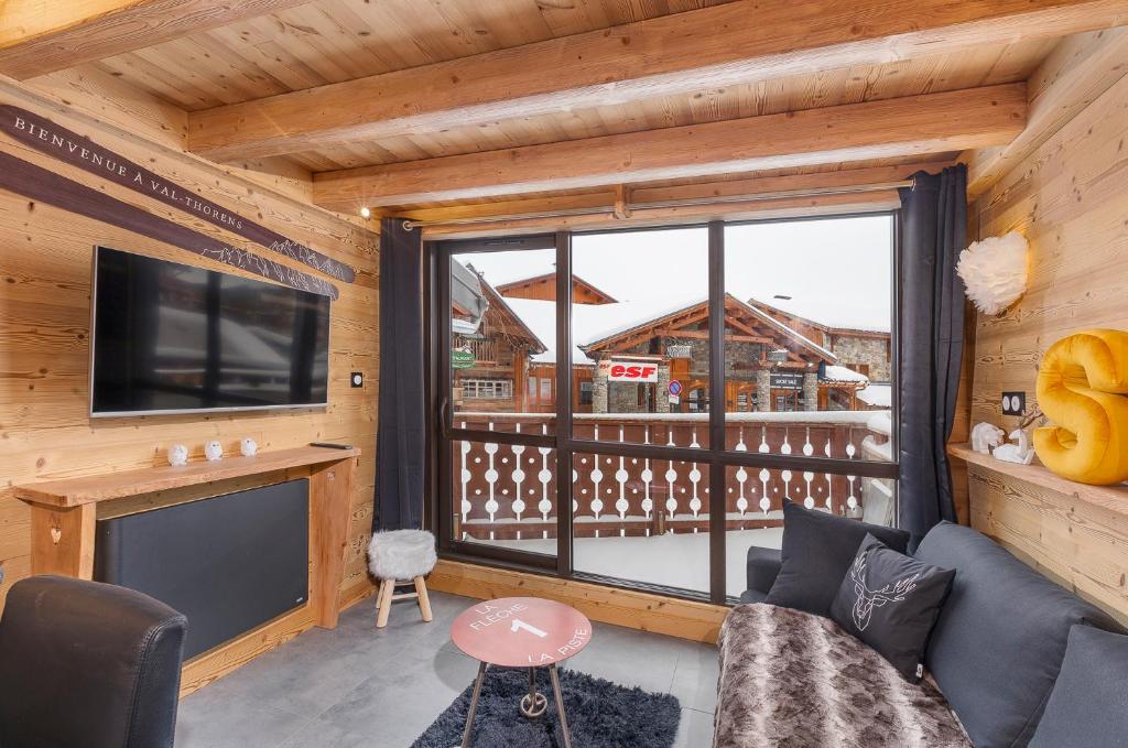 a living room with a tv and a large window at Val Thorens - Cosy Duplex Silveralp 004 in Val Thorens