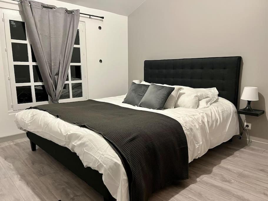 um quarto com uma cama grande e uma cabeceira preta em Appartement chaleureux proche RER/ CDG / Parc Expo em Sevran