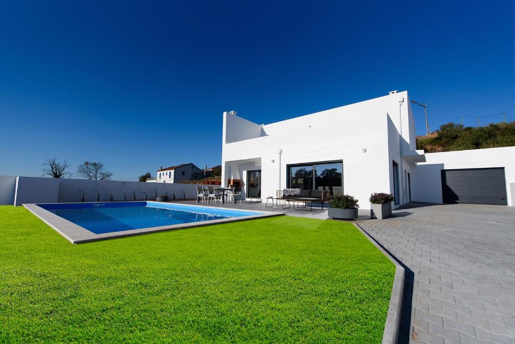 a white house with a swimming pool and a yard at Vakantiehuis Zilverkust Portugal 