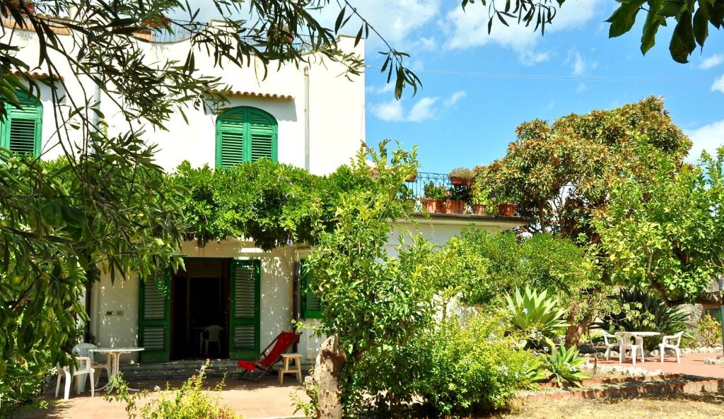 a house with green shutters and a garden at Seafront Apartments Garden House in Taormina