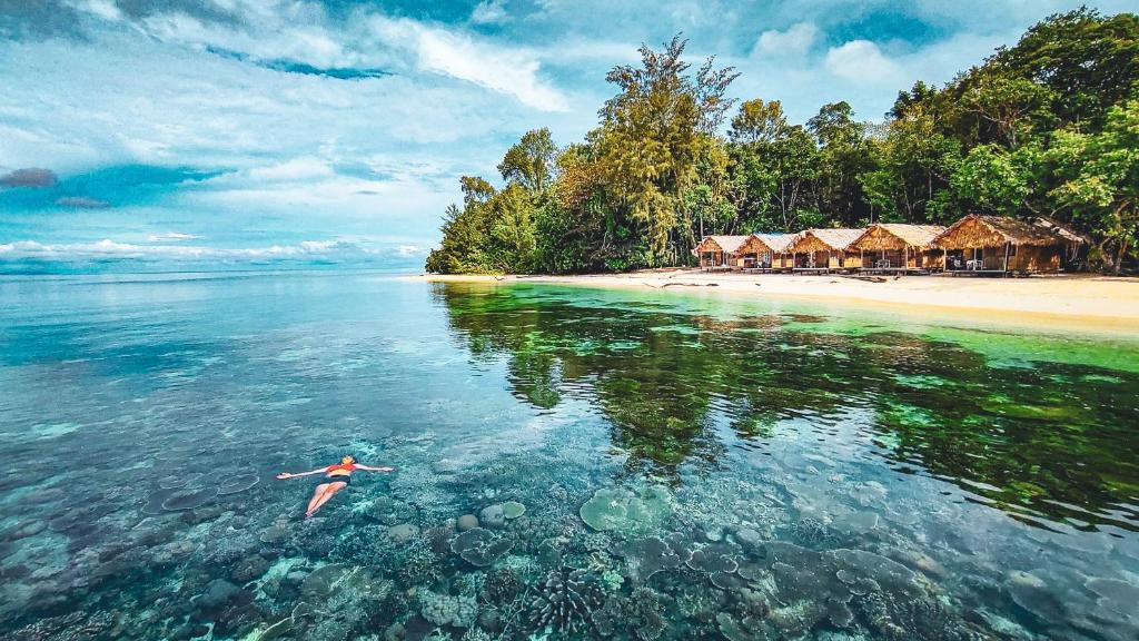 a person swimming in the water near a beach at Kamar Raja GuestHouse in Selpele