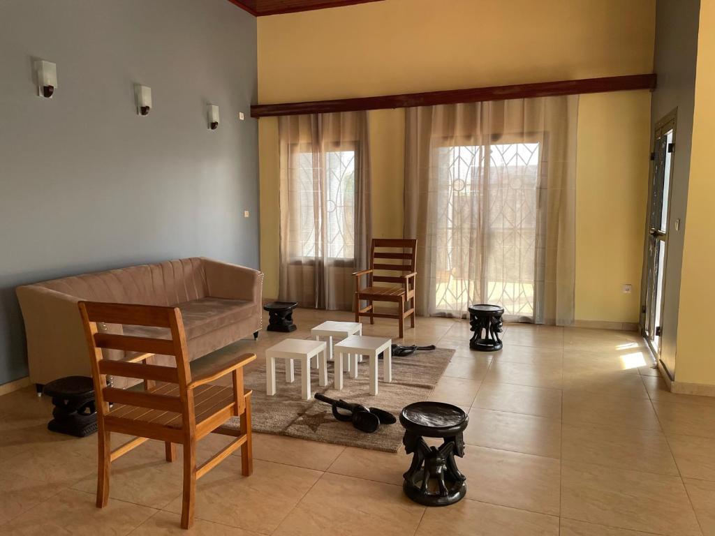 LesOiseaux في ياوندي: غرفة معيشة مع أريكة وكراسي ونوافذ