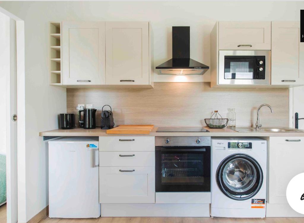 a kitchen with white cabinets and a washer and dryer at Cosy Loire, T2 neuf, front de Loire ,vue cathédrale,5min à pied centre ville et parking privé in Orléans