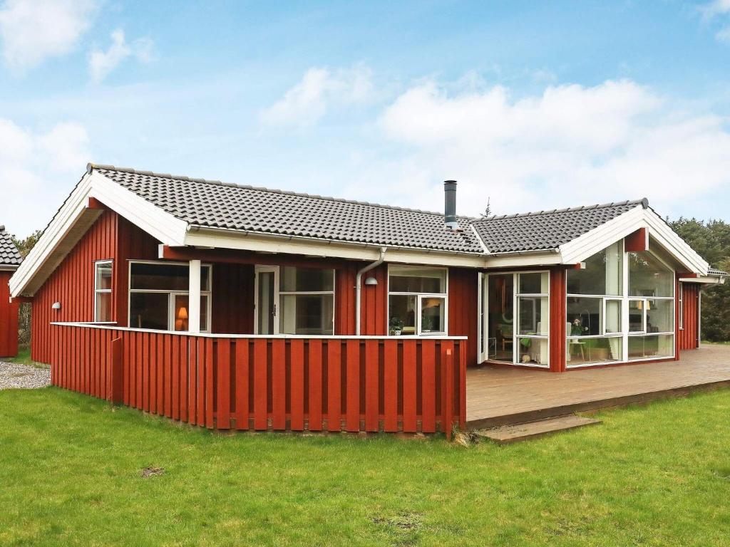ein rotes Haus mit einem roten Zaun im Hof in der Unterkunft 6 person holiday home in L kken in Løkken