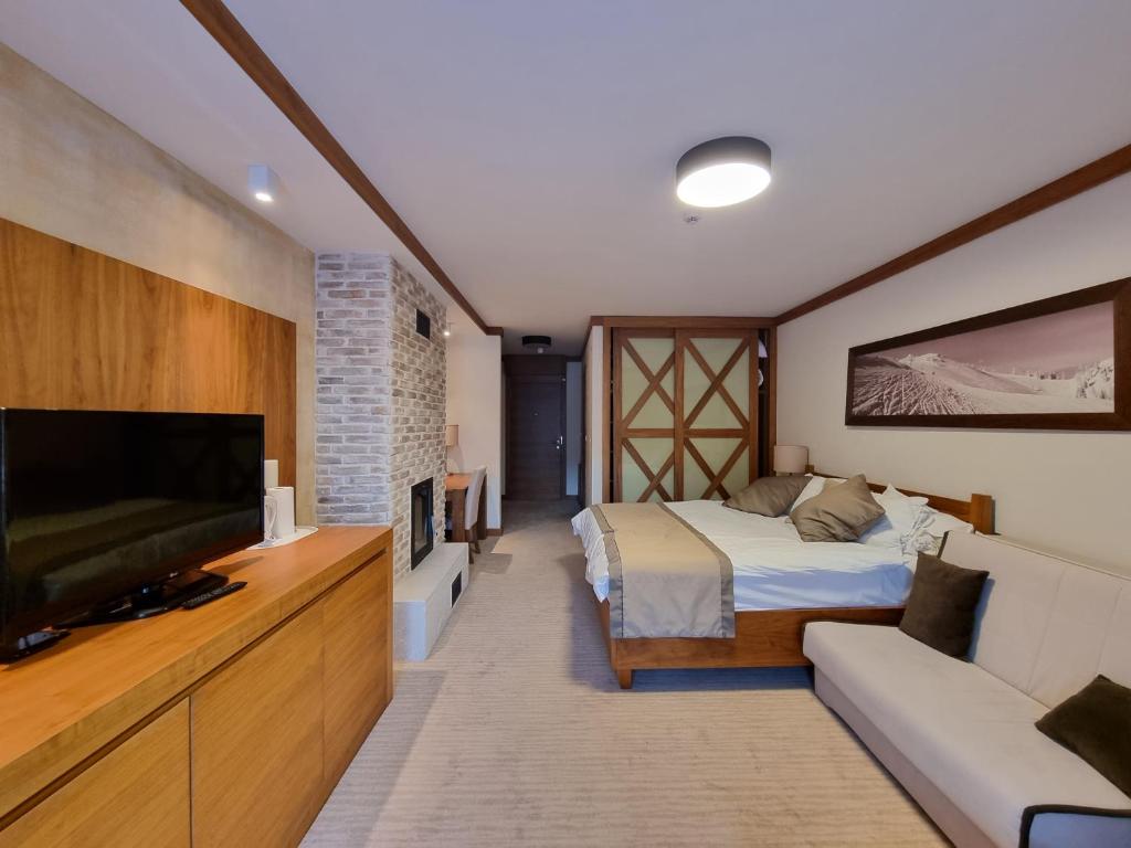 a bedroom with a bed and a flat screen tv at Apartman Lukas privatni app u sklopu aparthotela Vučko in Jahorina