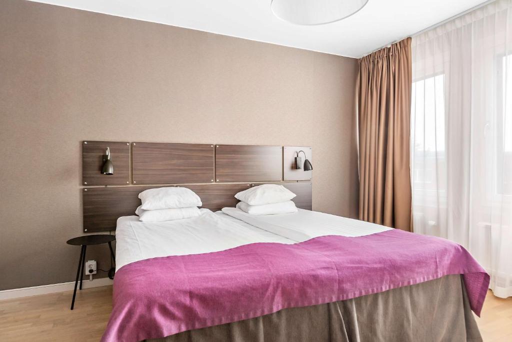 um quarto com uma cama grande e um cobertor roxo em Best Western Plus Park Airport Hotel em Arlanda