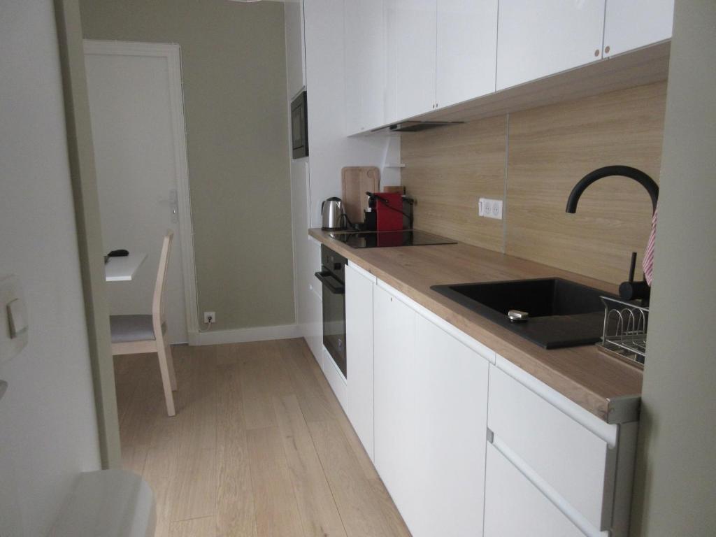 a kitchen with white cabinets and a black sink at Bourg-la-Reine : joli appartement de 20 m² in Bourg-la-Reine