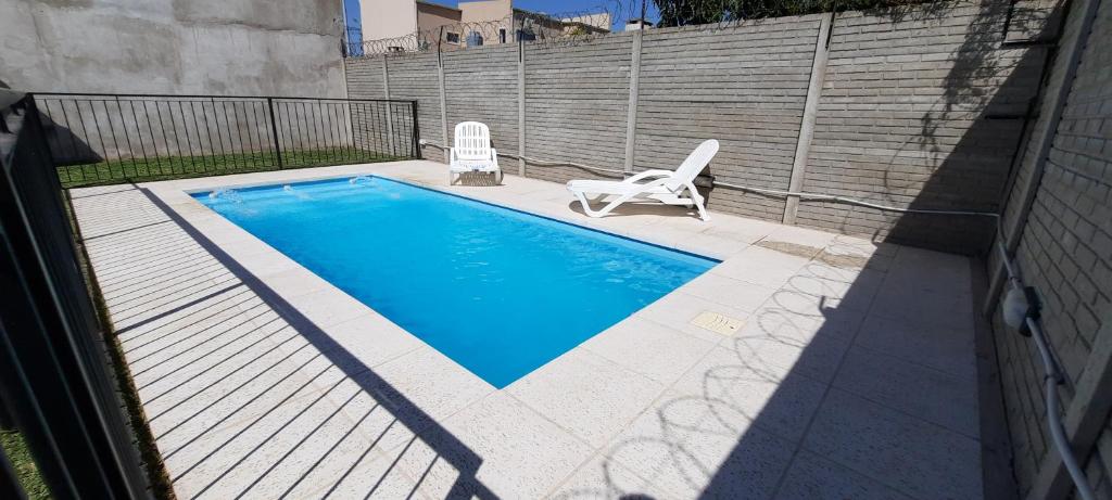 una piscina con 2 sillas de jardín junto a ella en Casa Los Zorzales en San Pedro