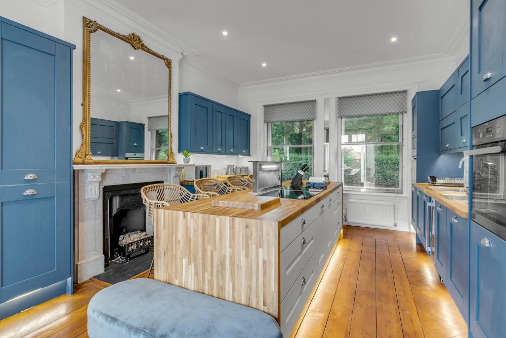 a kitchen with blue cabinets and a fireplace at Boardman Lodge, City centre, Park view, Games - Ginger & Gold ltd in Norwich