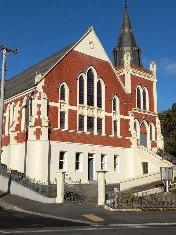 una gran iglesia roja y blanca con campanario en St David's on James Luxury apartments, en Dunedin