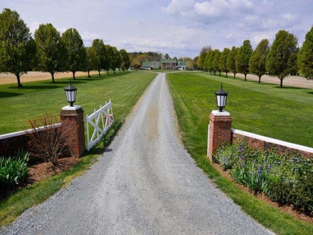 a gravel road with a fence and a bridge at Inn at Huntingfield Creek in Rock Hall
