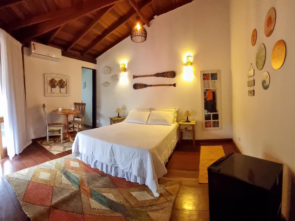 - une chambre avec un lit blanc et une table dans l'établissement Chalé dos Sonhos, à Ilhabela