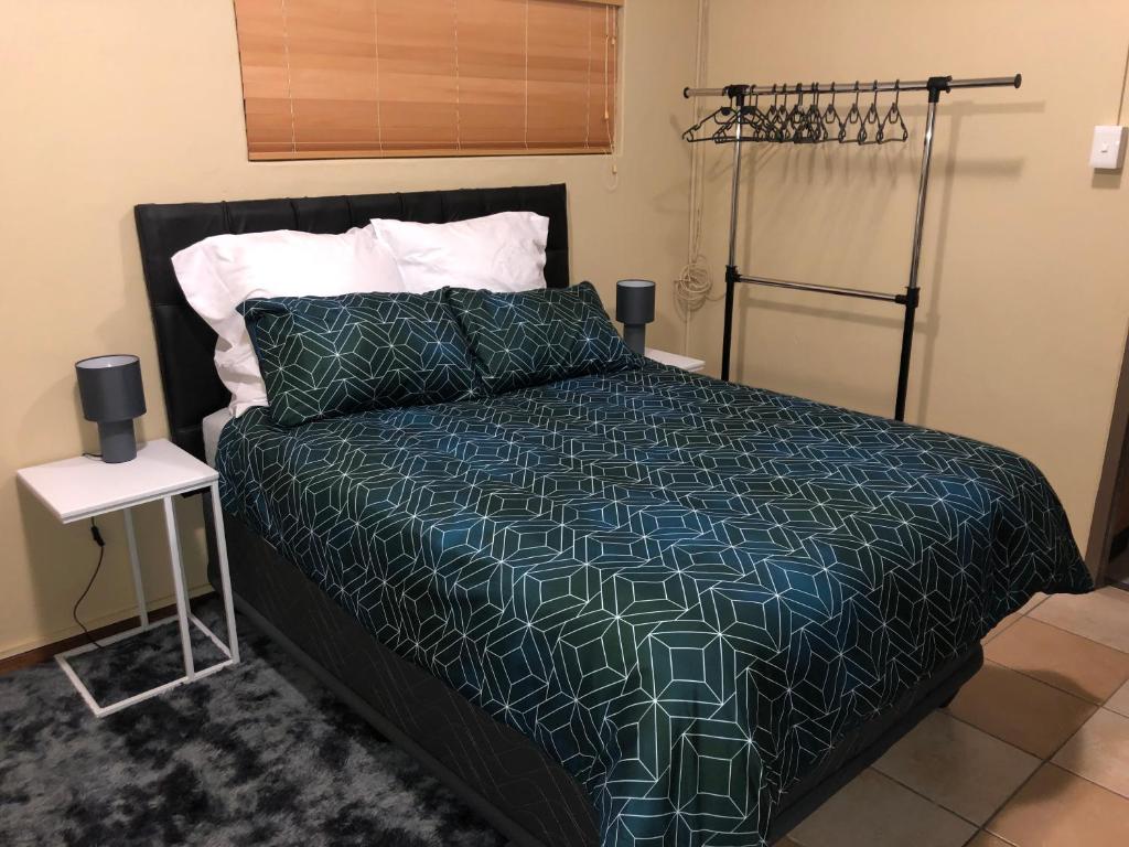 a bedroom with a bed with a blue and green comforter at Q’s in Empangeni