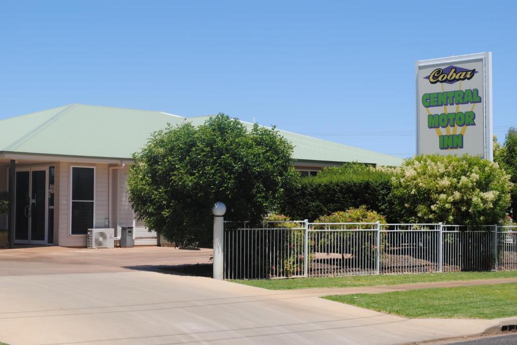 a building with a fence and a sign in front of it at Cobar Central Motor Inn in Cobar