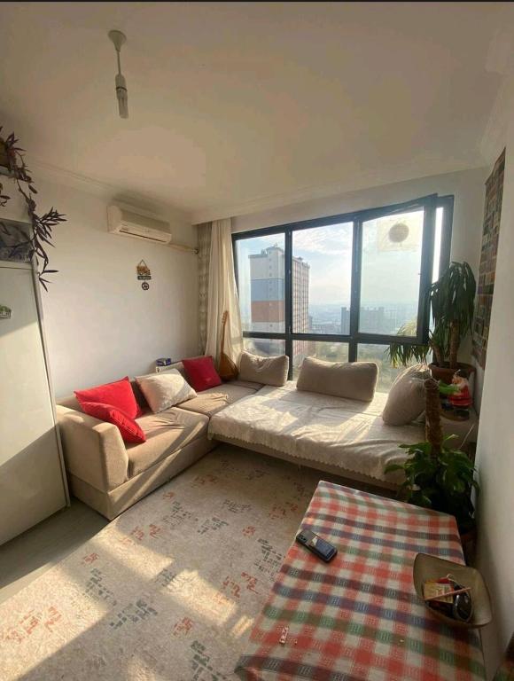 uma sala de estar com um sofá e uma grande janela em Üniversite kapısında köy manzaralı daire 
