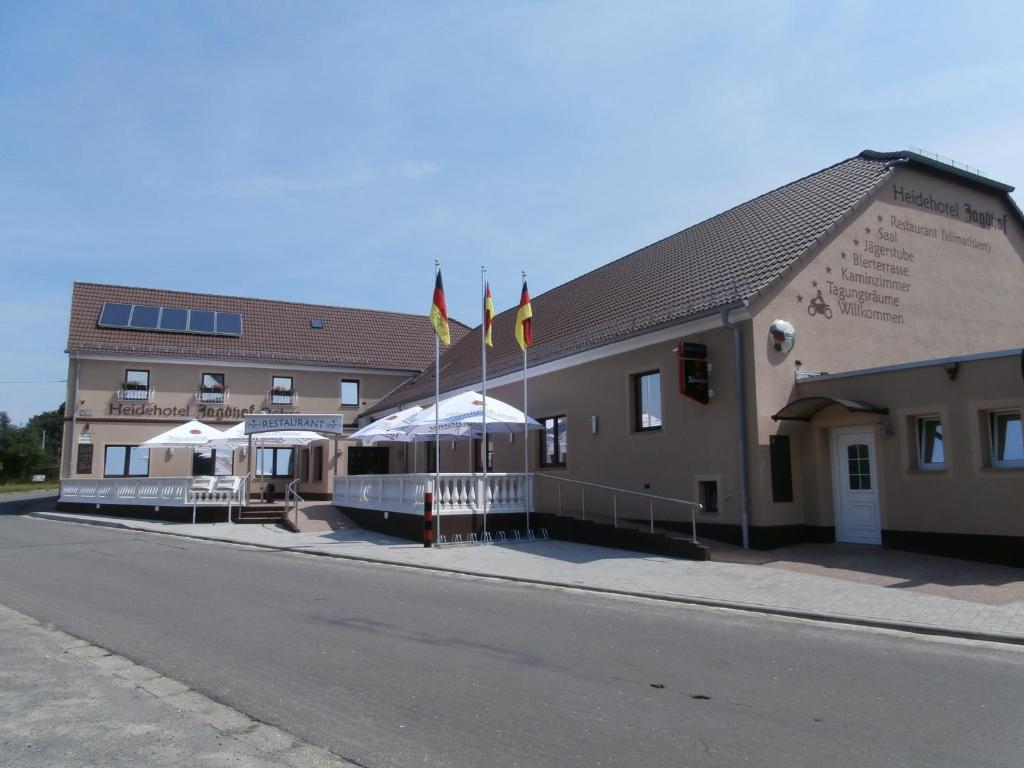 un edificio con banderas al lado de una calle en Heidehotel Jagdhof Dobra GmbH en Dobra