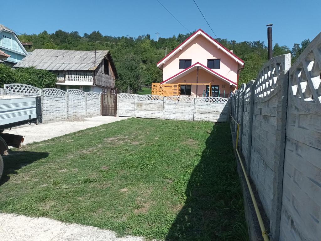 a fence in a yard with a house behind it at La Miruna in Comăneşti