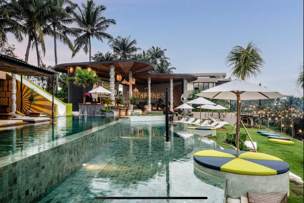 a pool at a resort with chairs and umbrellas at Soulshine Bali in Ubud