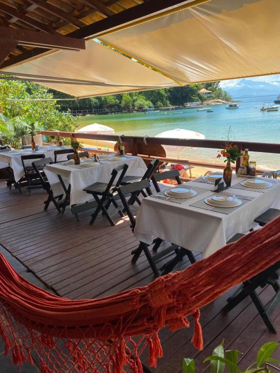 ein Restaurant mit Tischen und Stühlen auf einer Terrasse in der Unterkunft Pousada e Mergulho Dolce Vita in Praia Vermelha