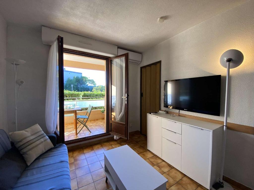 a living room with a blue couch and a flat screen tv at Appartement Sainte-Maxime, 2 pièces, 4 personnes - FR-1-226-500 in Sainte-Maxime